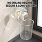 A stainless steel wire trash basket hanging from a wall-mounted suction cup holder, shown in a bathroom-like setting with a tiled wall and window frame. Large text at the top reads 'NO DRILLING REQUIRED SECURE & LONG-LASTING' with a blue arrow indicating the holder.