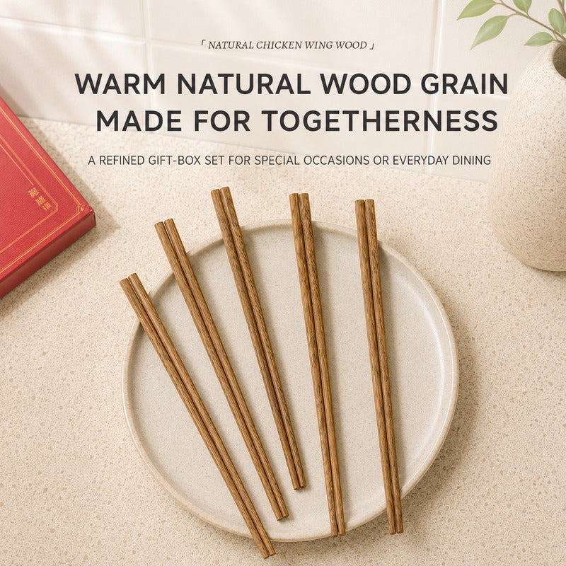 Five natural chicken wing wood chopsticks arranged on a round off-white ceramic plate, with promotional text above reading 'WARM NATURAL WOOD GRAIN MADE FOR TOGETHERNESS' and 'A REFINED GIFT-BOX SET FOR SPECIAL OCCASIONS OR EVERYDAY DINING.' A red book corner and a small vase are visible as styled props on a light beige surface.