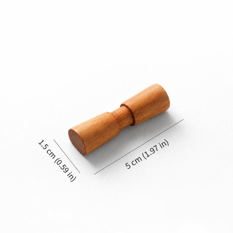 A small wooden cylindrical tool with a knurled center, shown on a white background with dimension lines indicating 1.5 cm in height and 5 cm in width.