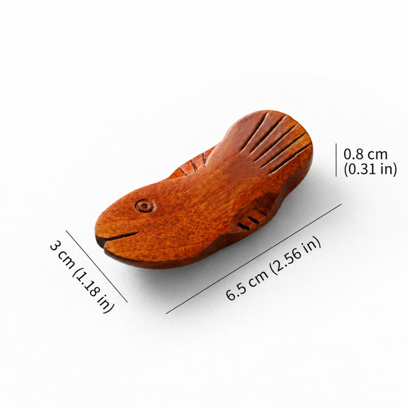 A small carved wooden fish-shaped object on a white background with dimension lines and measurements showing 3 cm length, 6.5 cm width, and 0.